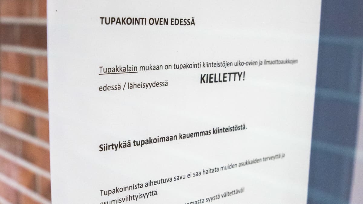 Tupakointi oven edessä kielletty -lappu ulko-ovessa.