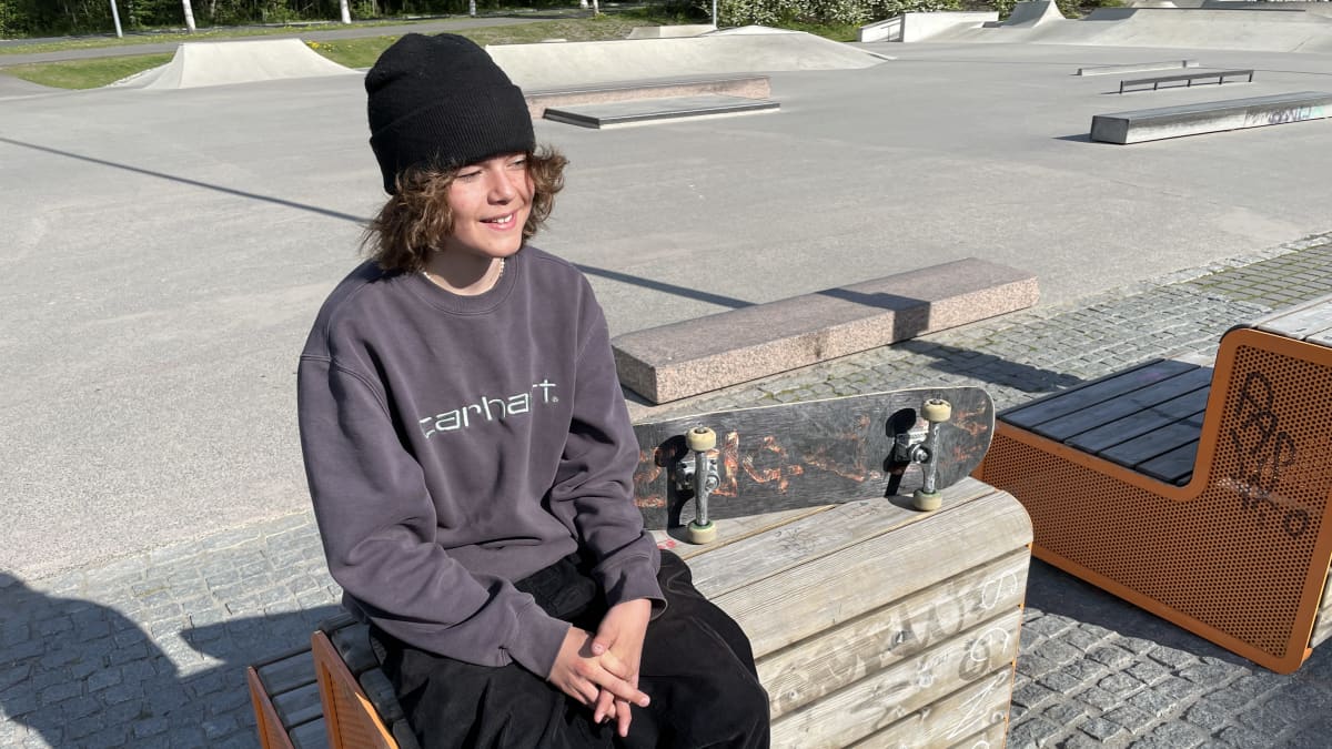 Nuori poika istuu penkillä ja vieressä skeittilauta.
