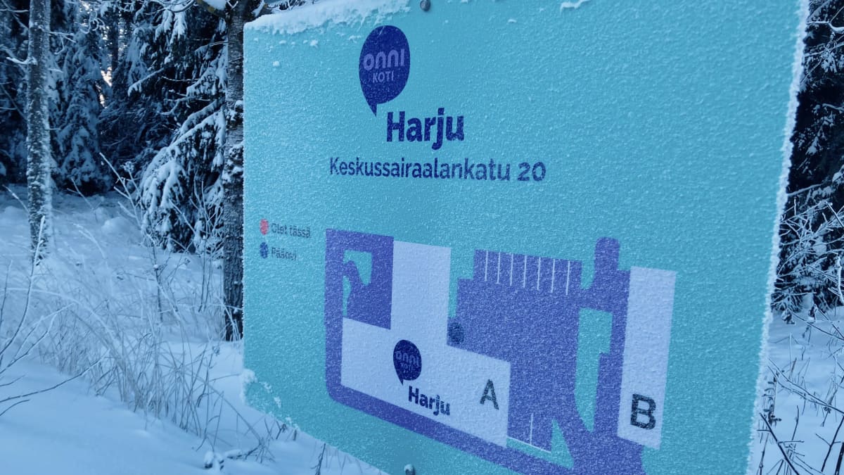 Onnikoti Harjun opastekyltti, johon on merkitty palvelukotiin kuuluvat rakennukset. Kyltti on kuurassa, ympärillä lumihanki.