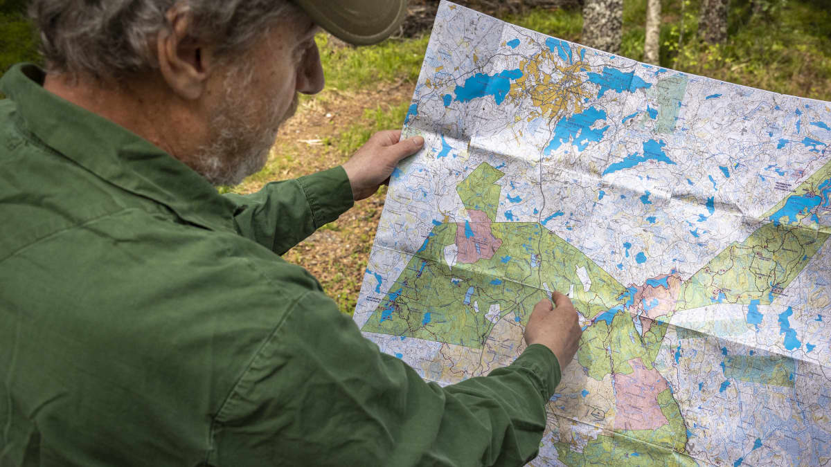 Markku Karvonen tutkii karttaa luonnossa.