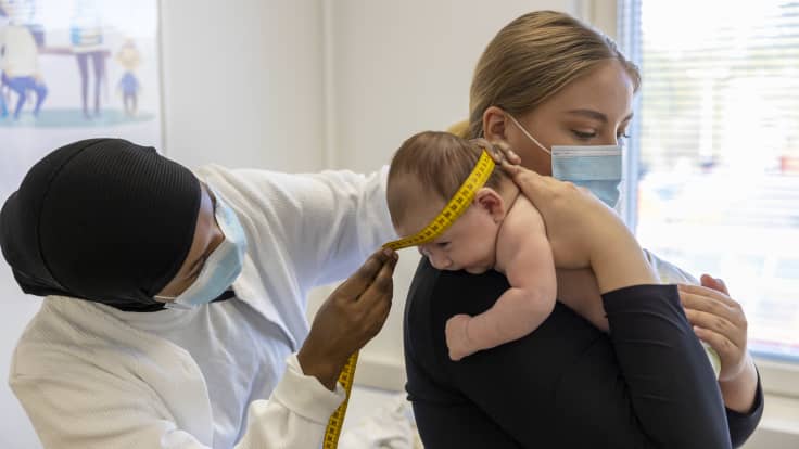 Terveydenhoitaja mittaa vauvan päänympärystä.