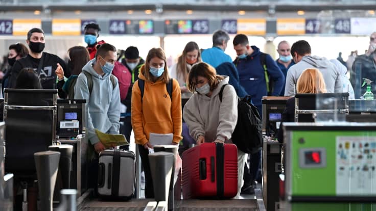 Matkustajat laittavat matkalaukkujaan lentoaseman tavarahihnalle.