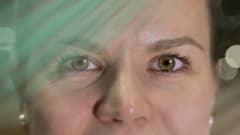 Petra Tapolan silmät katsovat kameraan. Kuvan yli kulkee vihreää utua ja sen reunoilla on valkoisia valoympyröitä.
