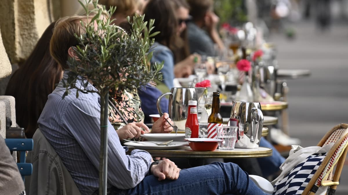 Ihmisiä nauttimassa lämpimästä säästä The Cock -ravintolan terassilla Helsingissä 3. kesäkuuta 2021.