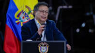 Gustavo Petro puhuu puhujakorokkeella mikrofoniin. Takana Kolumbian lippu.