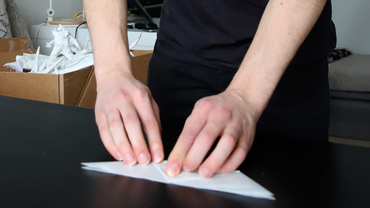 Origamitaiteilija Juho Könkkölä taittelee paperia.