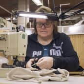 Nainen ompelee villaisia alusasuja Ruskovillan tehtaalla.