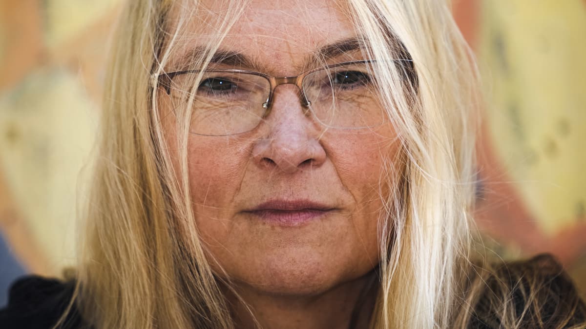 Kirsi Marie Liimatainen katsoo suoraan kameraan, tukka tuulessa heiluen.