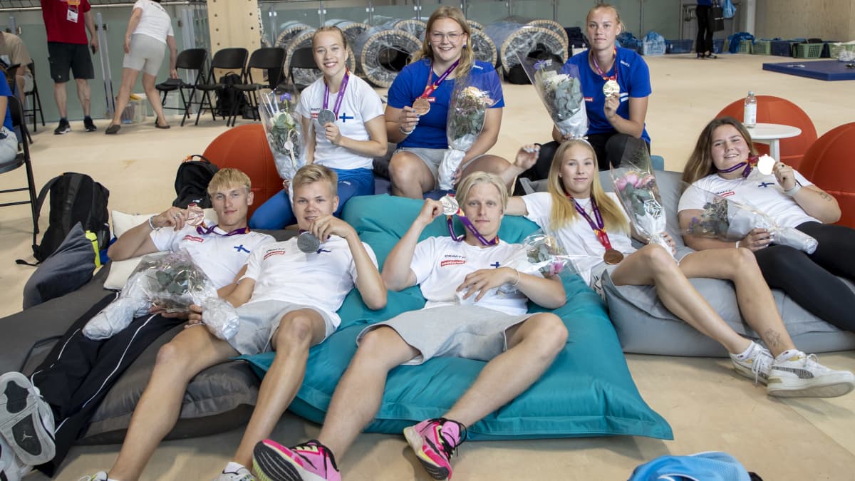 Kahdeksan suomalaisurheilijaa poseeraa nuorten EM-mitalien kanssa Espoossa.