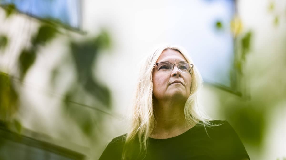 Kirsi Marie Liimatainen seisoo kerrostalon edessä jossa asui lapsena.