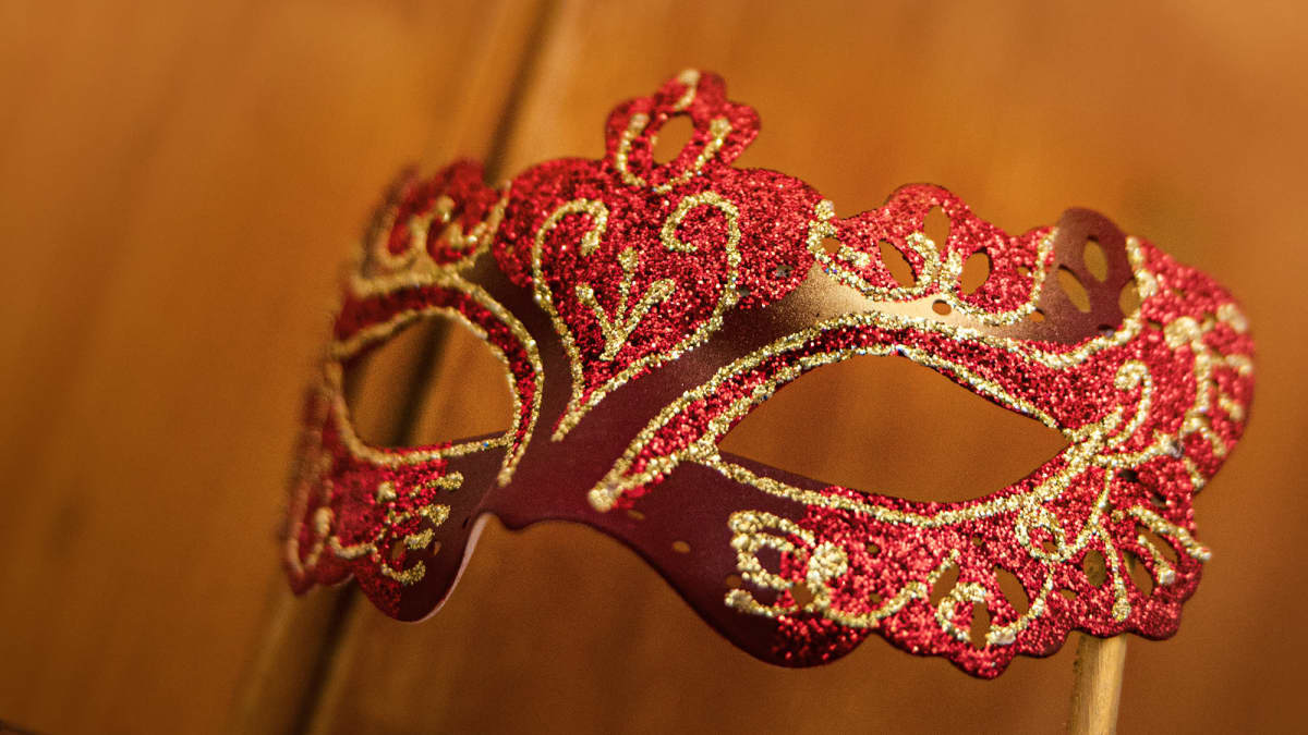 Oopperan punaisella ja kullalla koristelu tikun varassa kannateltava maski.