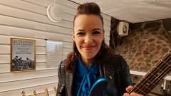 Erja Lyytinen med gitarr, i bakgrunden hennes pristavla för bästa europeiska bluesgitarrist