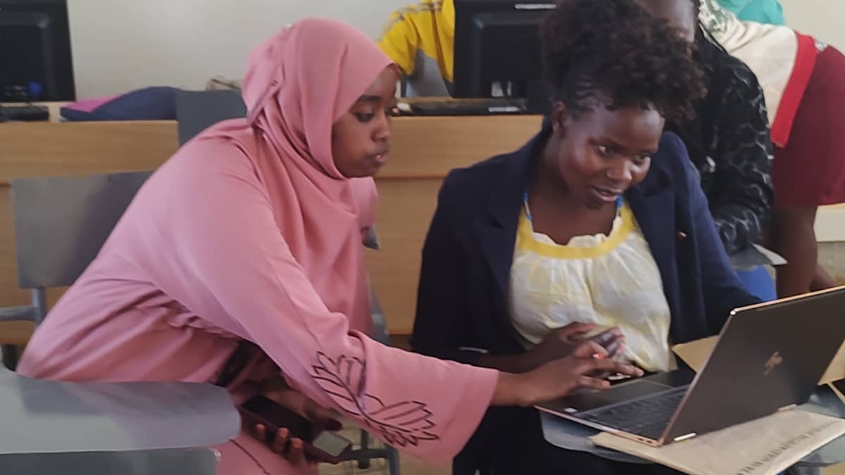 Kaksi kenialaista nuorta naista luokkahuoneessa katsomassa läppäriä yhdessä. 