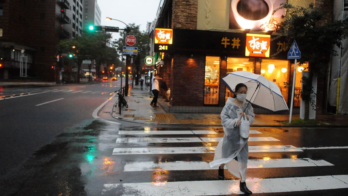 Tokiossa nainen suojaa itseään sateenvarjolla ja kävelee pitkin tyhjentyneitä katuja. Tokiossa varaudutaan voimakkaaseen taifuuniin.