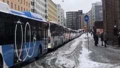 Bussijono Helsingin Hämeentiellä. Bussi on jumittunut lumisohjoon Kurvissa.