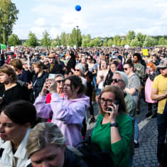 Mielenosoittajia Töölönlahden tapahtumapuistossa kuuntelemassa puheita ja musiikkia.
