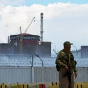 Venäläissotilas seisoo vahdissa ydinvoimalan rakennusten edessä.