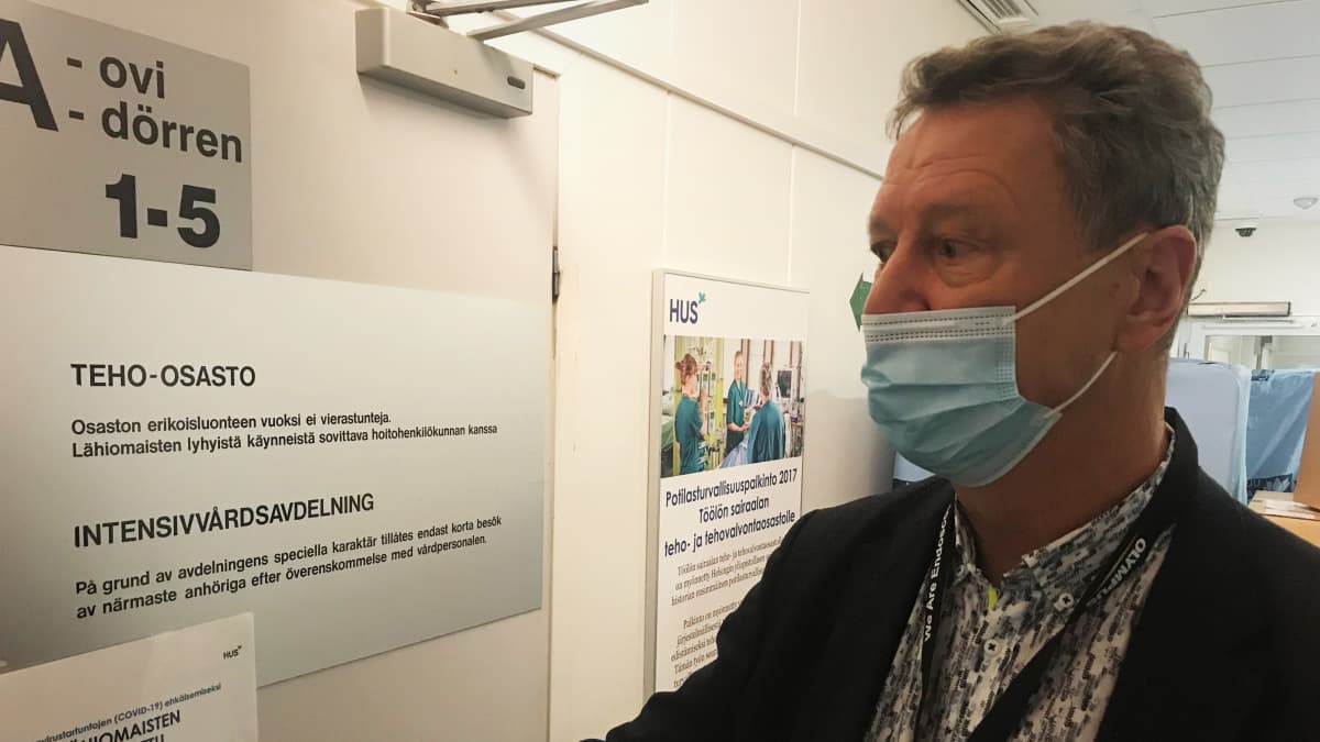 HUS:in valmiusyksikön ylilääkäri Eero Hirvensalo tarttuu teho-osaston ovenkahvaan sairaalan käytävällä