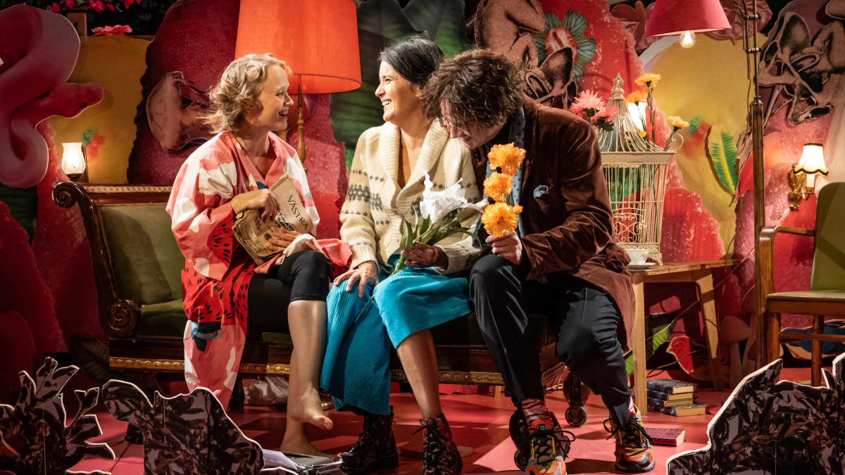 Kuvassa on kolme näyttelijää istumassa: Ella Mettänen, Vilma Melasniemi ja Miiko Toiviainen. He nauravat.