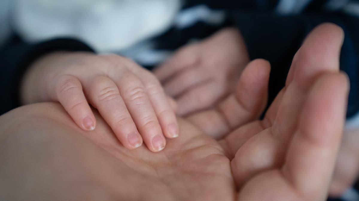 Pikkuvauvan käsi äidin kämmenellä.