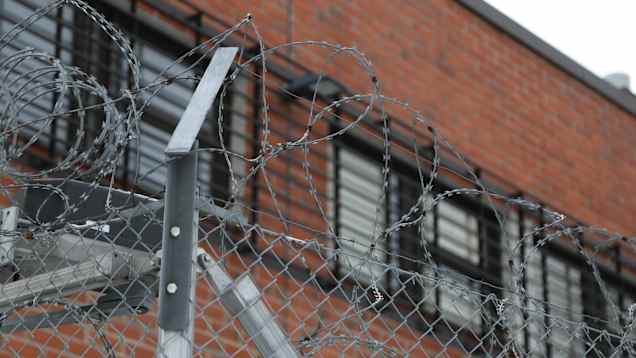 Barbed wire in front of a red-brick building. 