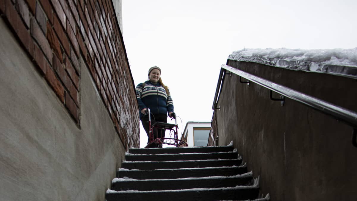 Marja Puustinen seisoo ulkona lumisten portaiden yläpäässä.