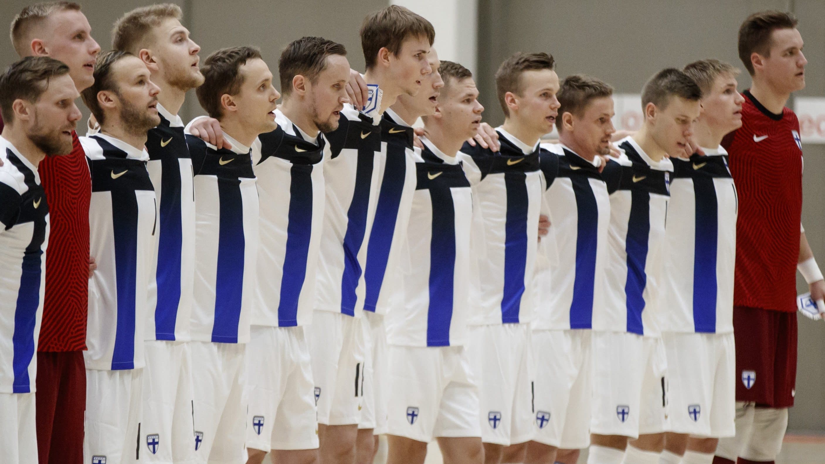 Suomen futsalmaajoukkue rivissä pelaajien kädet toistensa harteilla.