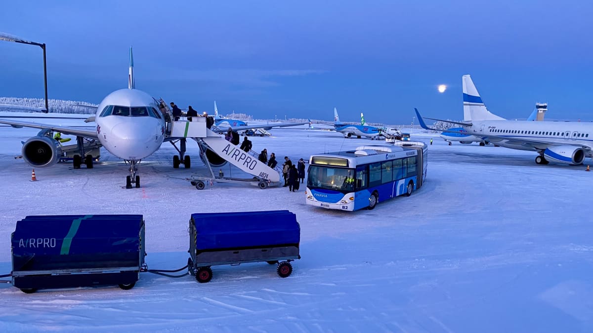 Rovaniemen lentokenttä, ulkomaisia koneita, ihmisiä nousemassa koneeseen. 
