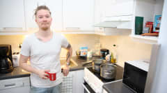 Janne Lahtinen seisoo keittiössään kahvikuppi kädessään.