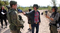 Televisio toimittaja ja kuvaaja haastattelevat sotamiestä.