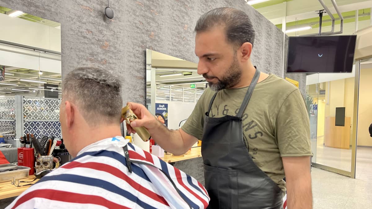 NiBarber -parturin yrittäjä Dilsher Yousef leikkaa asiakkaan hiuksia.