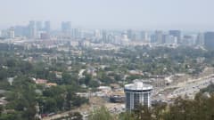 Los Angelesin kaupunki näkyy mottoritien ja puiden takana. Etualalla on pyöreä tornihotelli.   