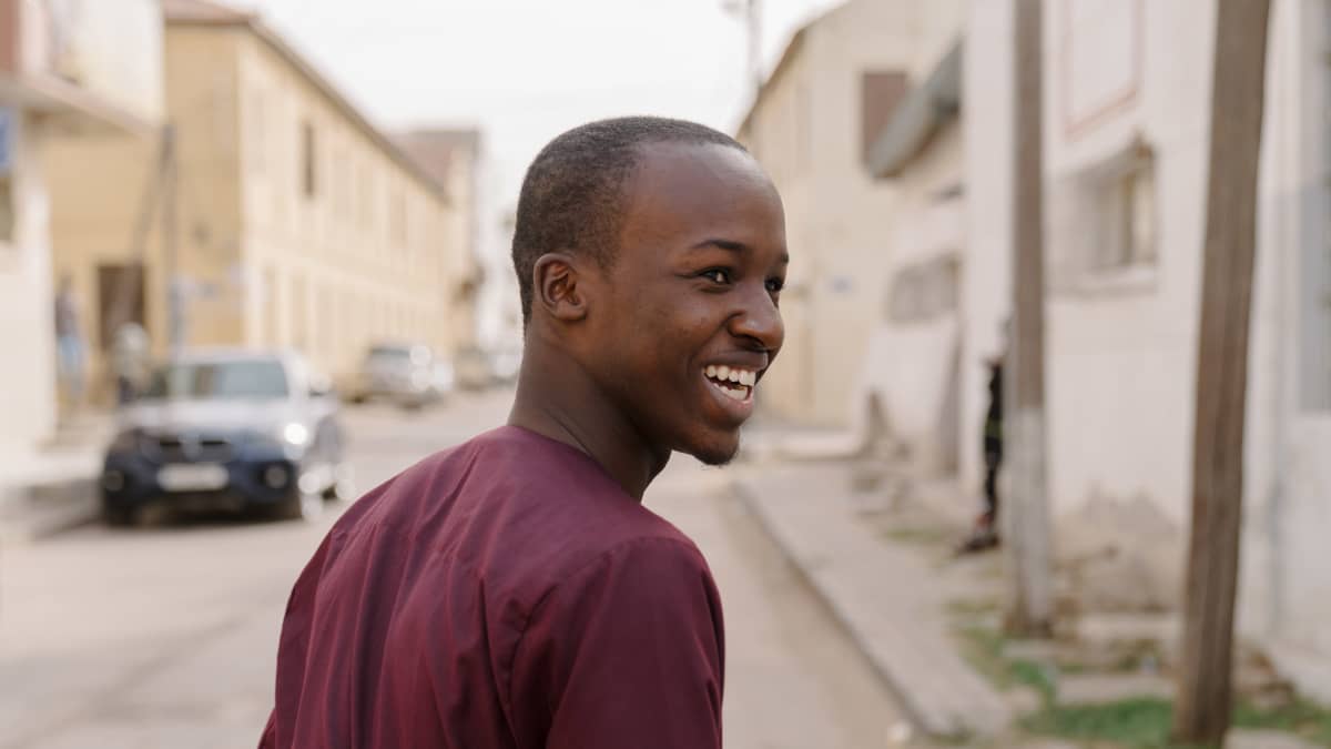 Nuori ilmastoaktivisti Yero Sarr kävelee autiolla kadulla ja katsoo hymyilleen taakseen.
