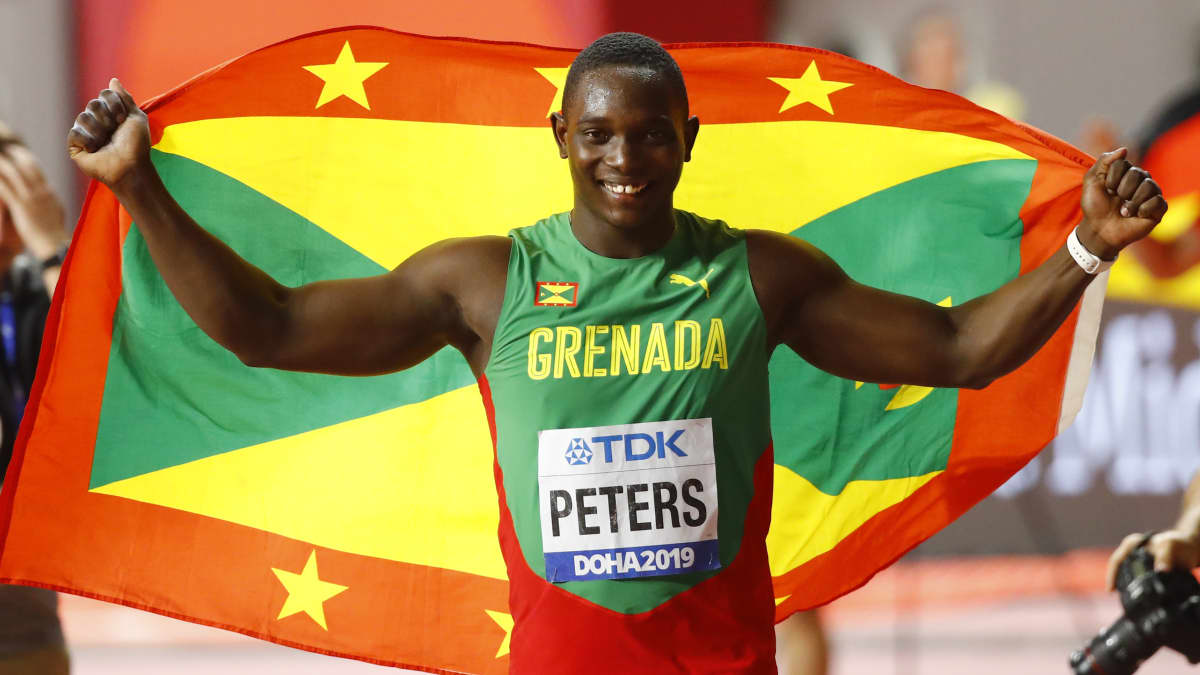 Anderson Peters håller upp Grenadas flagga bakom sig.