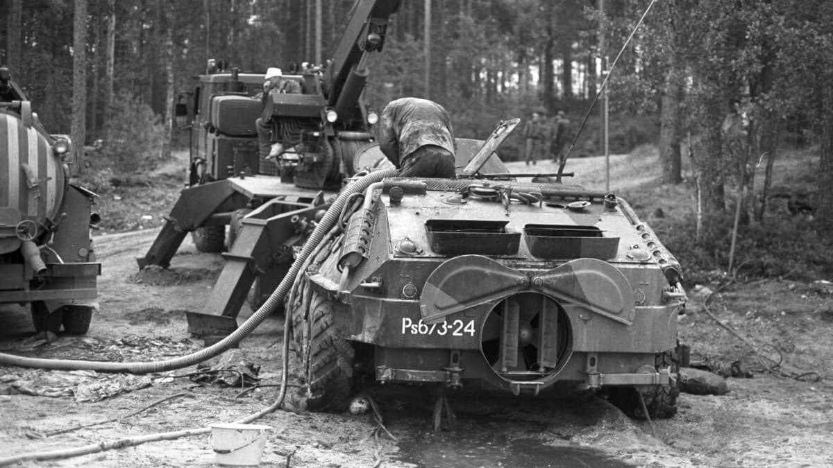 Arkistokuva jossa Saimaaseen uponnut BTR-60 vaunu on nostettu rannalle ja puolustusvoimien henkilökunnan jäsen on tyhjentämässä sitä vedestä pummpausletkulla kesällä 1991
