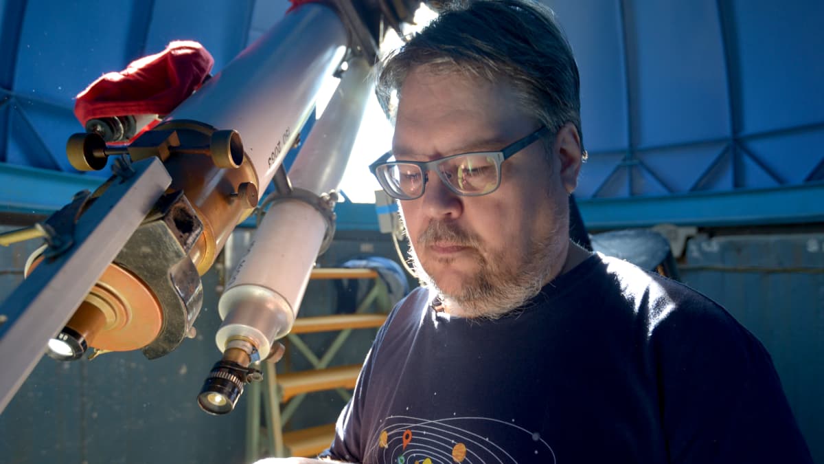 Tähtitieteen harrastaja Arto Oksanen valmistelee tähtitornissa kaukoputkea.