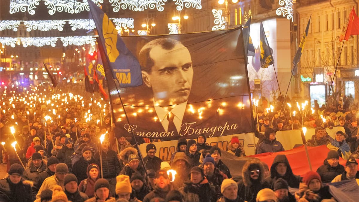 Soihtukulkue marssii kadulla. Marssijoilla on suuri plakaatti, jossa on Stepan Banderan kuva.