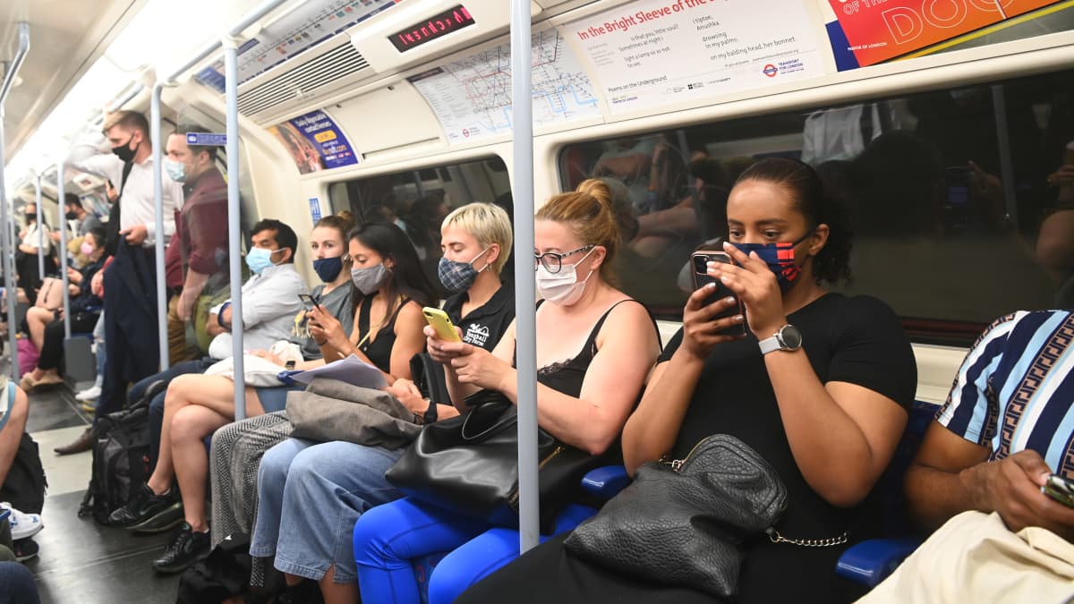 Ihmisiä ruuhkaisessa metrossa maskit kasvoilla.