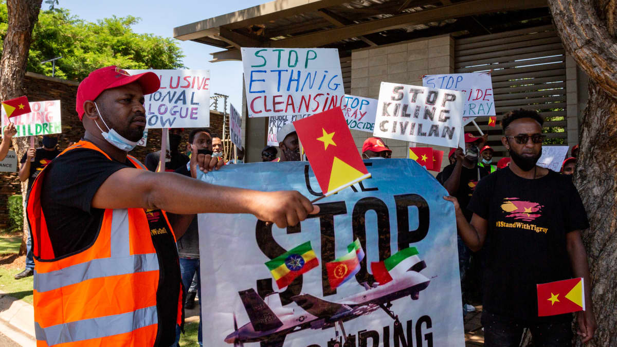 Eteläafrikkalaiset Tigrayn sotaa vastustava mielenosoittajat kantavat kylttejä, joissa kehotetaan lopettamaan pommitus