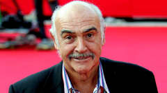 Sean Connery hymyilee punaisella matolla.