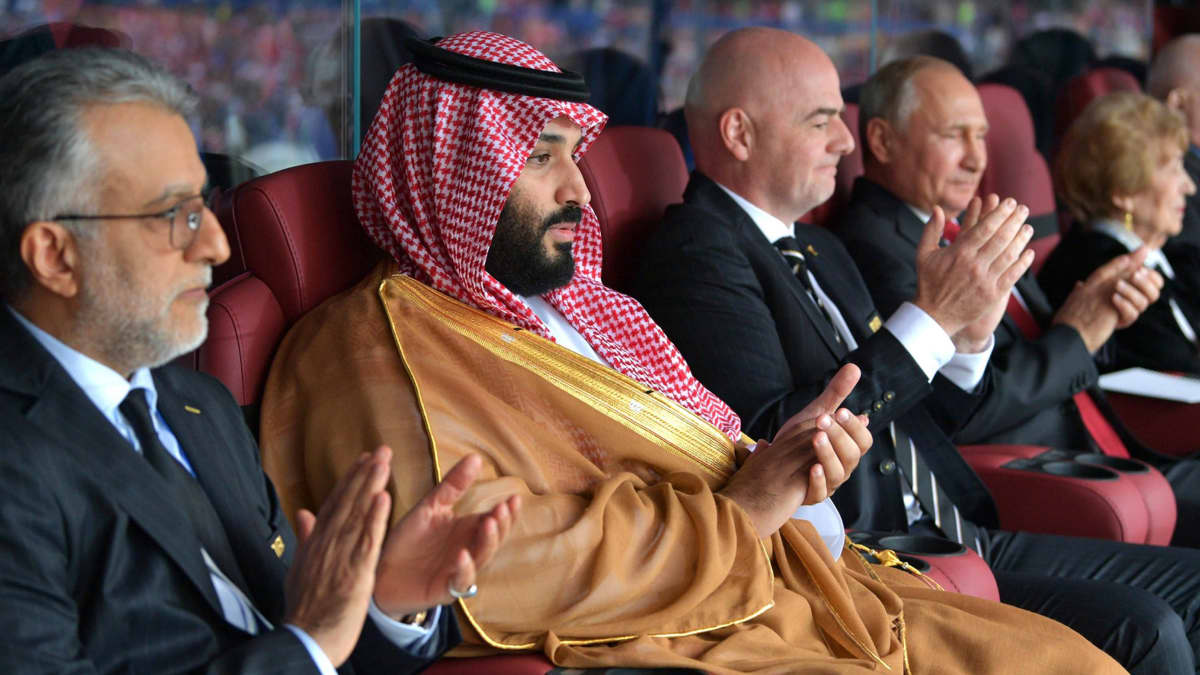 Muhammad bin Salman, Gianni Infantino ja Vladimir Putin istuvat vierekkäin MM-kisoissa 2018.