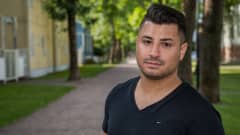 Eric Rimon katsoo kameraan ulkona. Taustalla asuinrakennuksia.