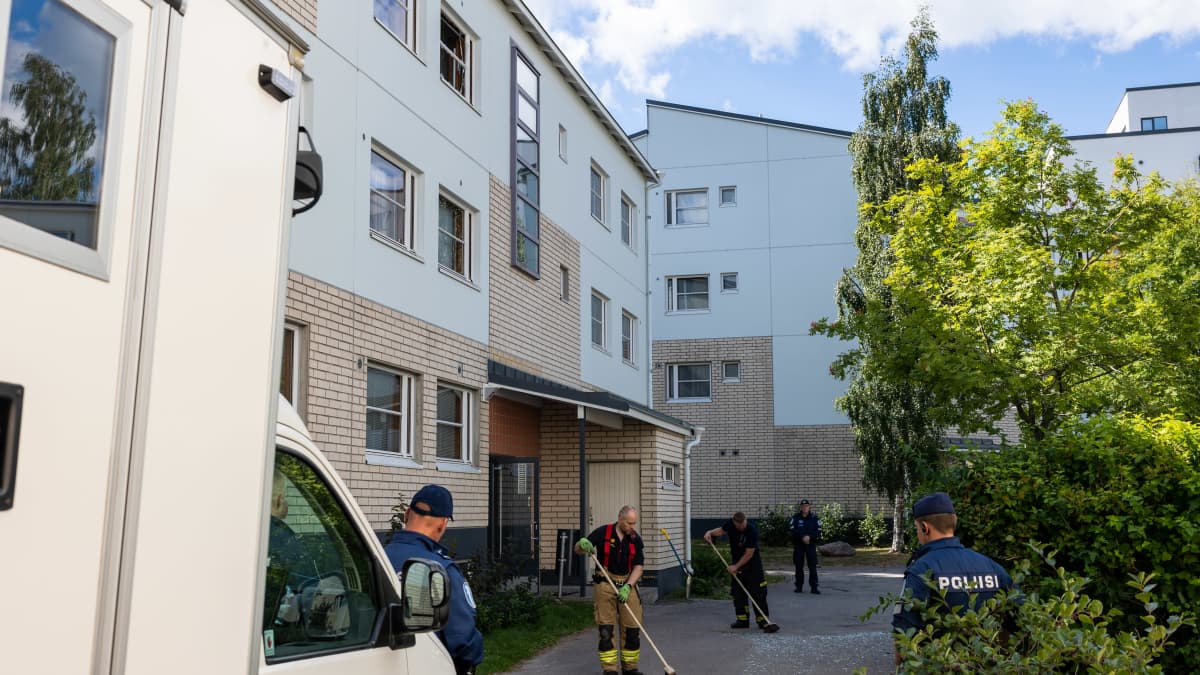 Poliisit lakaisevat lasinsiruja kerrostalon pihalla Vantaalla räjähdysonnettomuuden jälkeen.