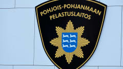 Pohjois-Pohjanmaan pelastuslaitoksen logo paloaseman seinässä.