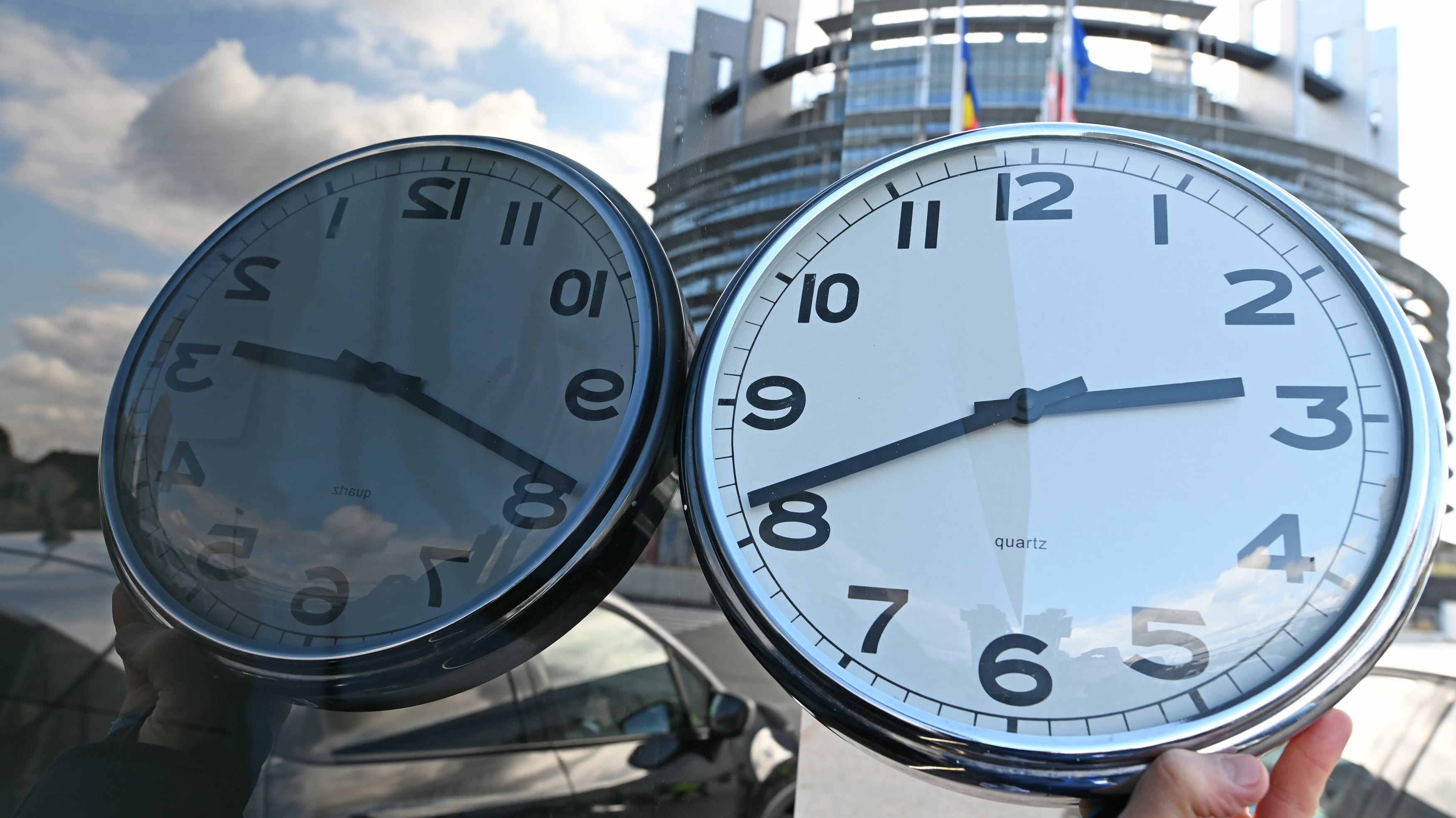 Kello heijastuu lasiseinästä ja taustalla näkyy EU rakennus Strasbourgissa.