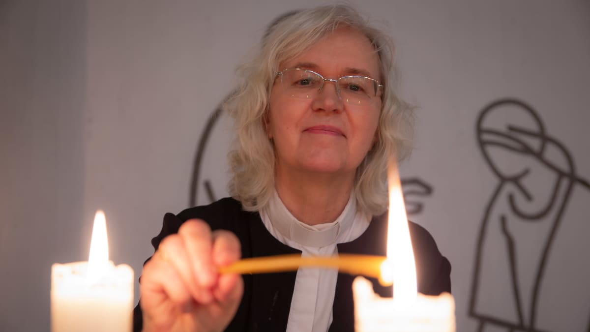 Kappalainen Marketta Antola sytyttää kynttilän Vuosaaren kirkossa.