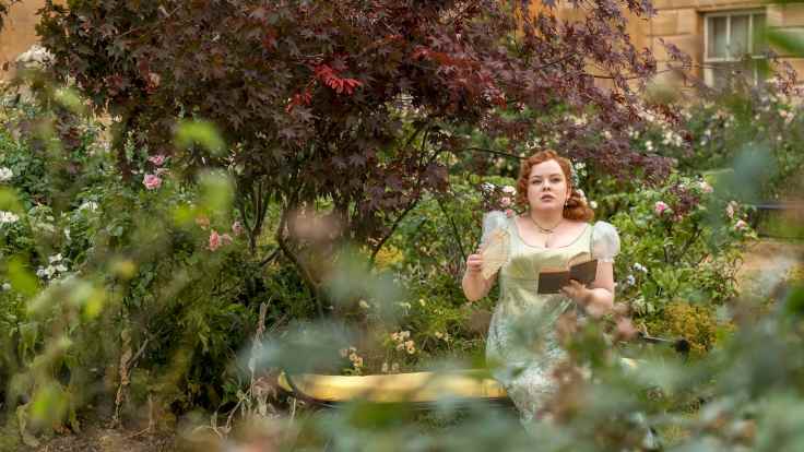 Nainen istuu penkillä puutarhassa Netflixin TV-sarjassa Bridgerton.
