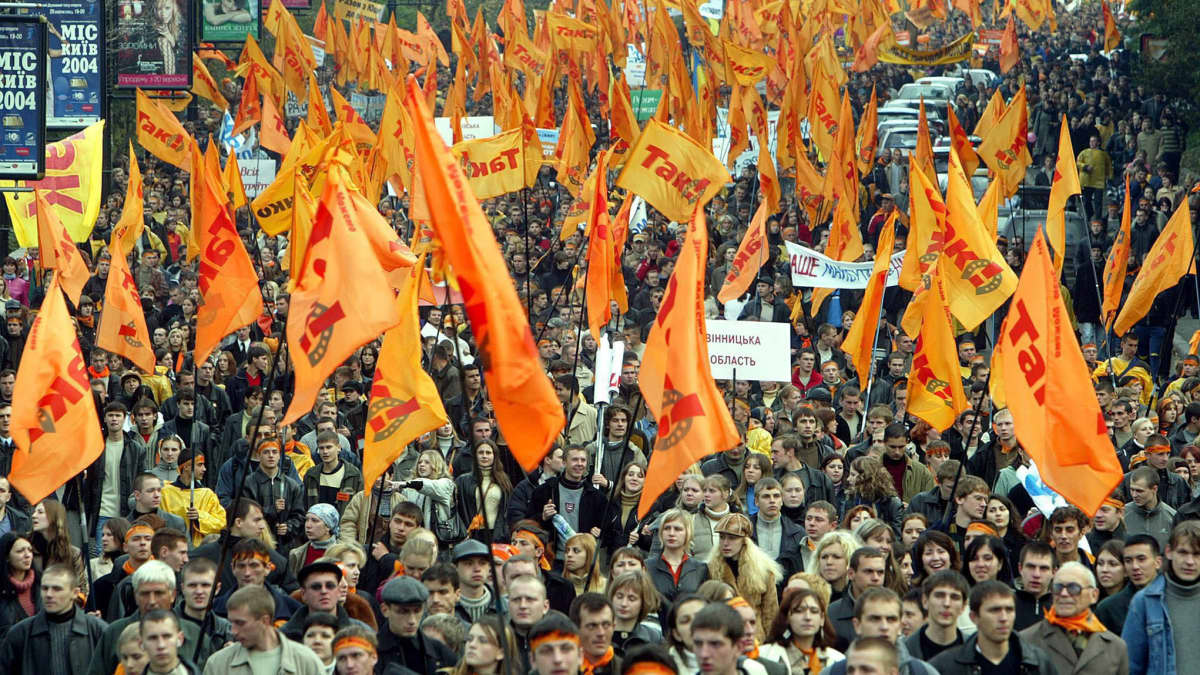 Väkijoukko heiluttaa oransseja lippuja. 