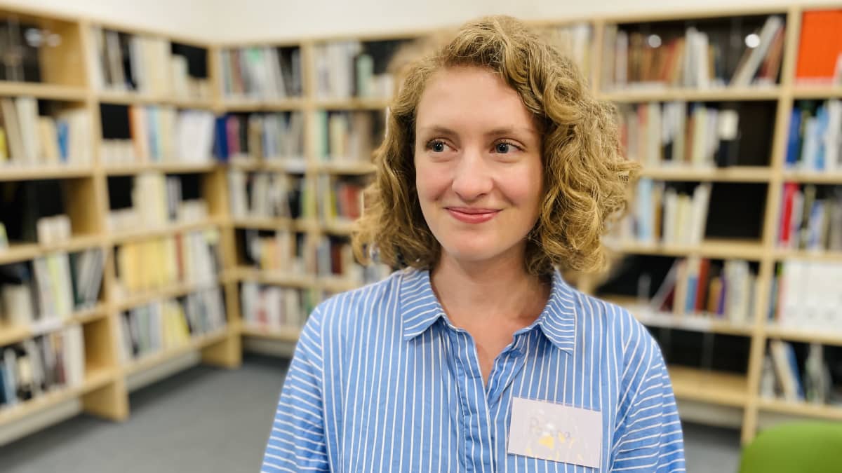 Polina Razorilova hymyilee ja katsoo kameran ohi kirjastossa.