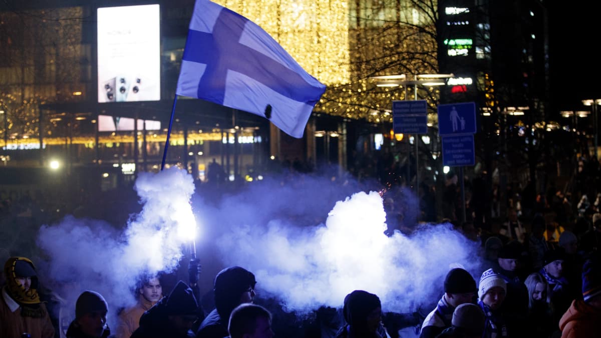 Suomen lippu liehuu savujen yllä.